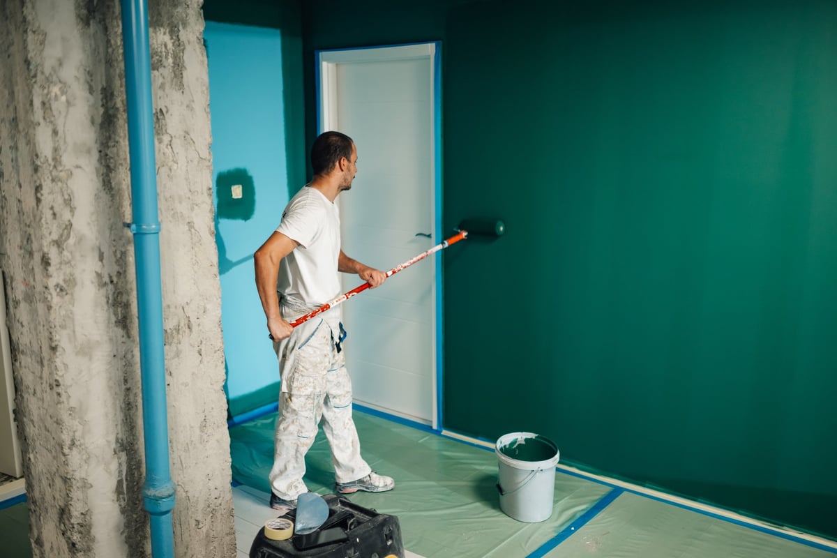 Professional painter applying paint to an interior bedroom wall